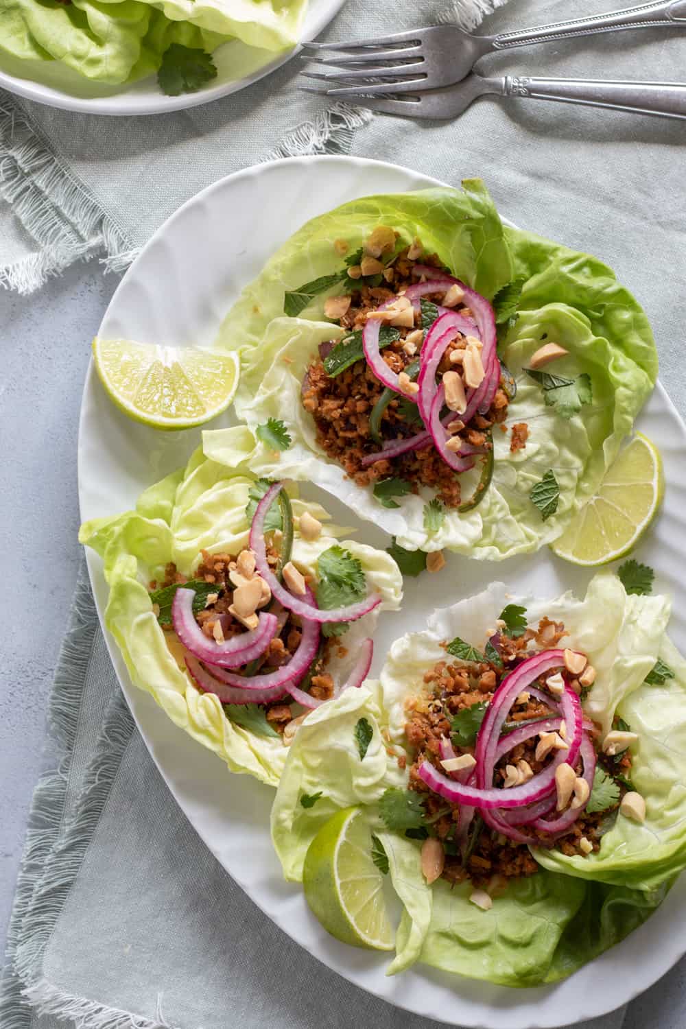 overhead shot of three Thai Larb lettuce cups on a white platter.