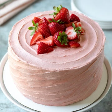 whole 3-layer cake decorated with pink vegan frosting and strawberries on top