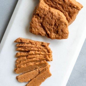 sliced seitan steaks on a white platter.