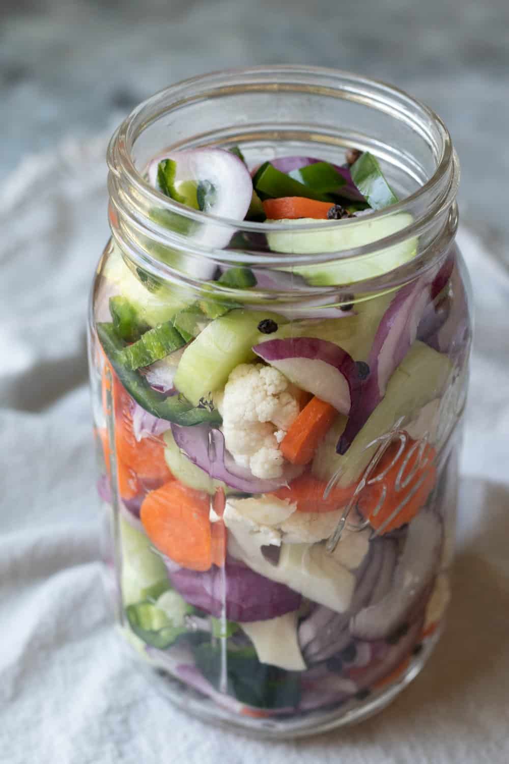 A mixture of fresh vegetables plus peppercorns in a 32 ounce glass jar.