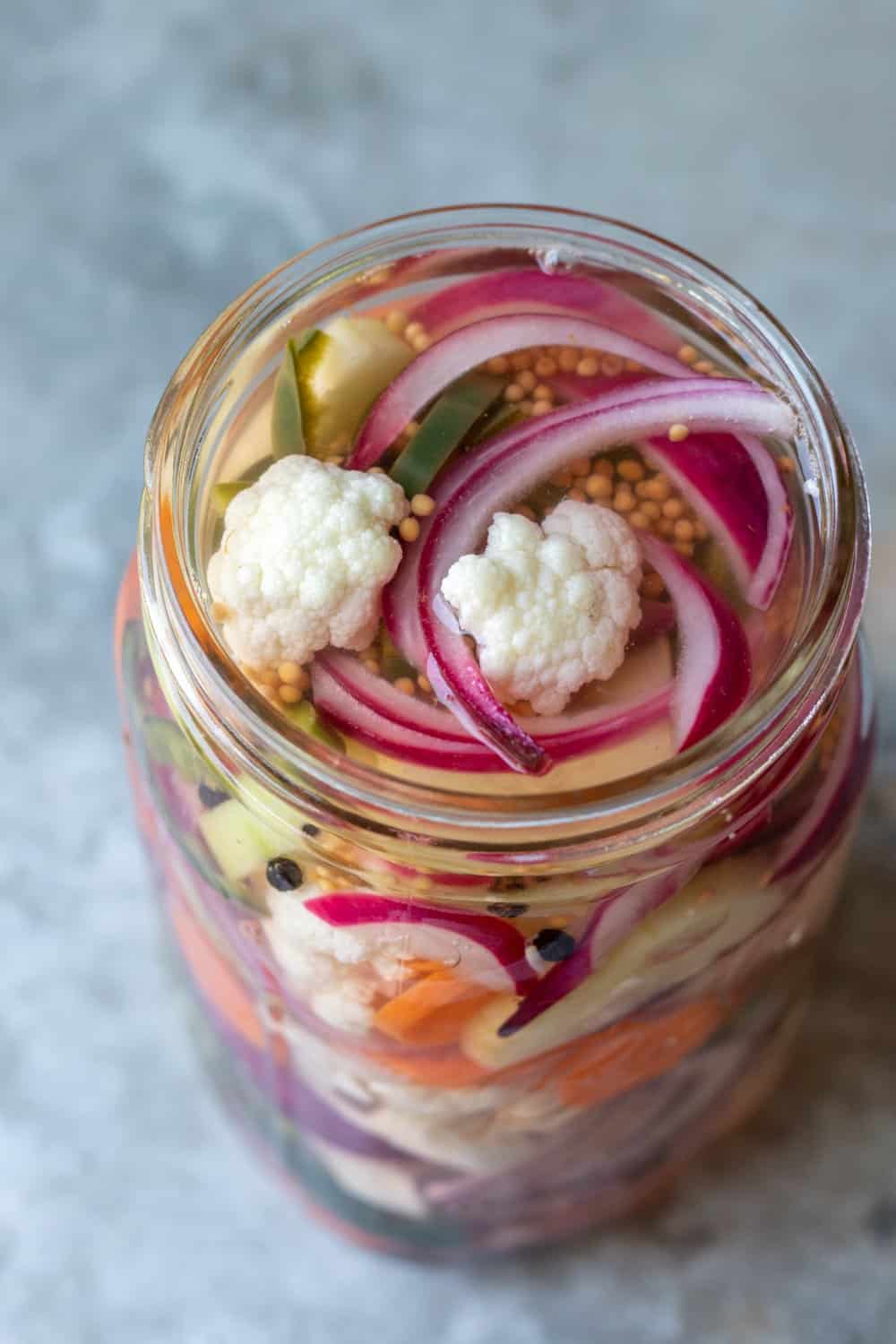 A jar of vegetables with brine poured over, ready to be refrigerated.