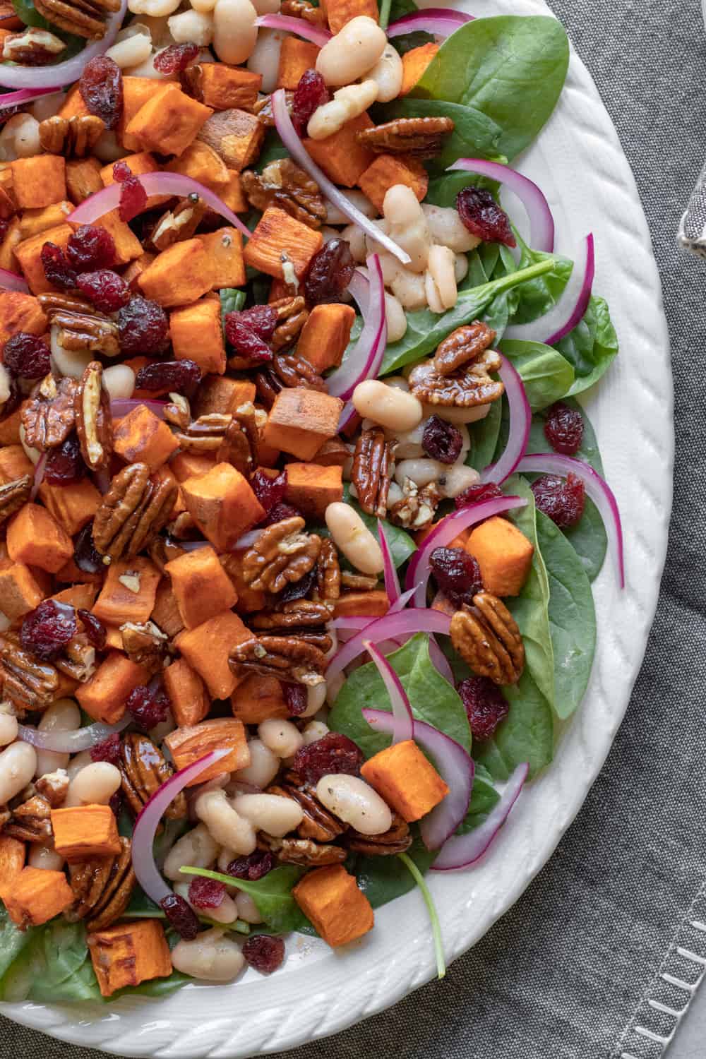 fully assembled spinach and sweet potato salad on a white platter.