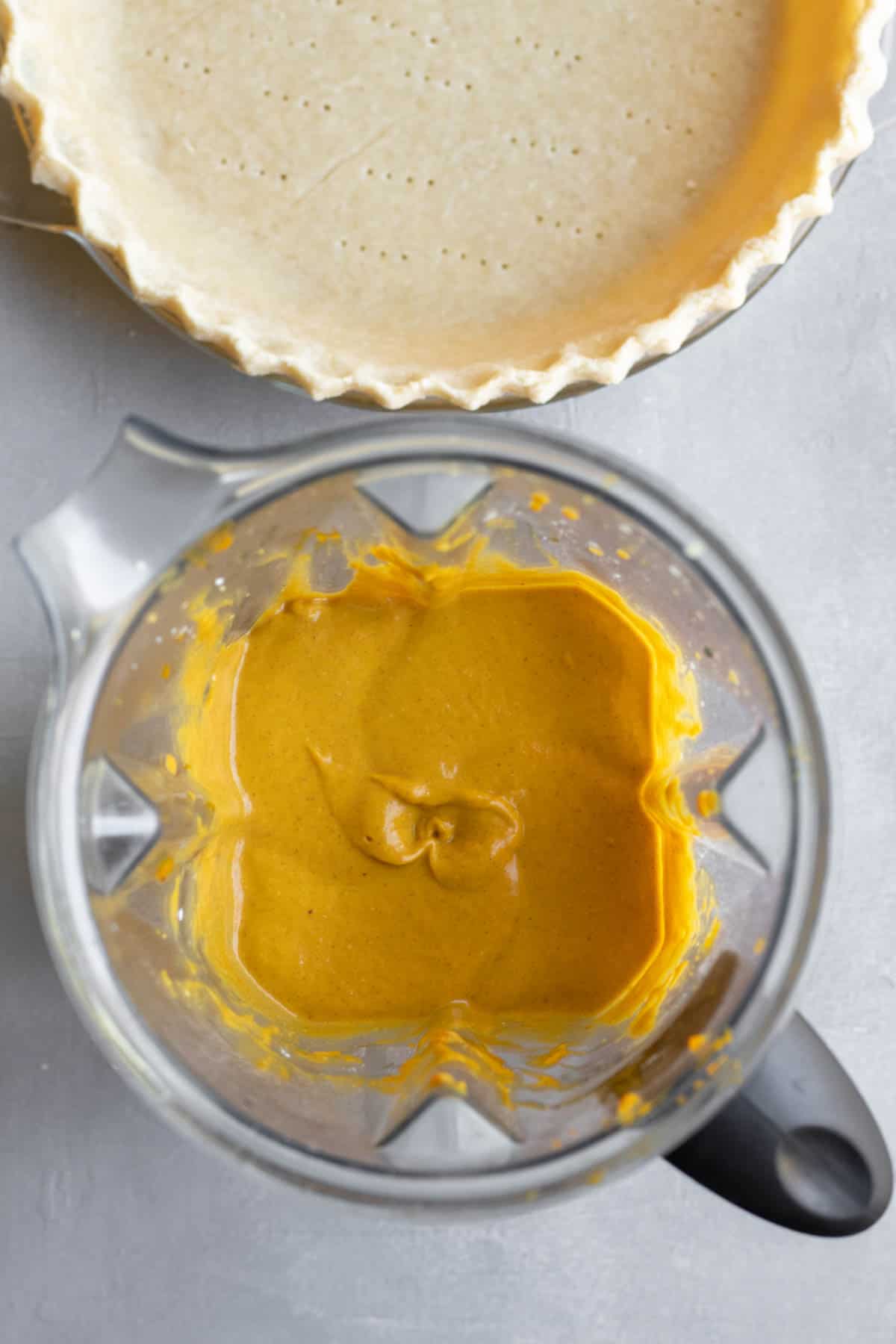 empty pie shell and creamy pumpkin pie mixture in blender.