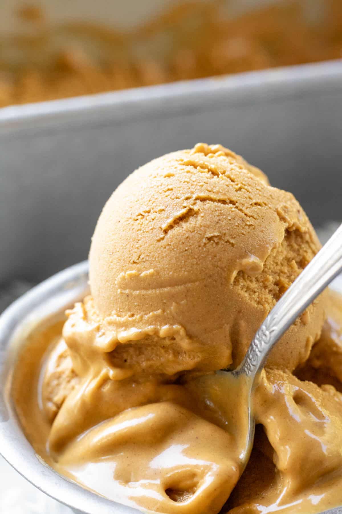 melty close up shot of vegan pumpkin ice cream in a small silver dish.