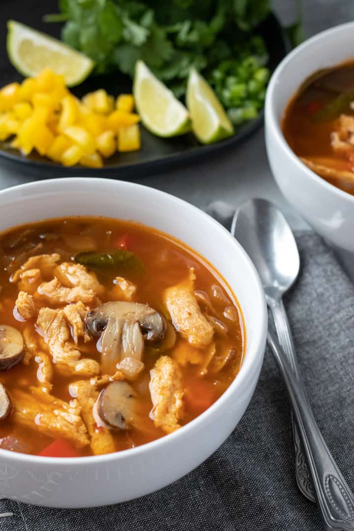 spicy thai soup in white bowls - easy tom yum copycat recipe.