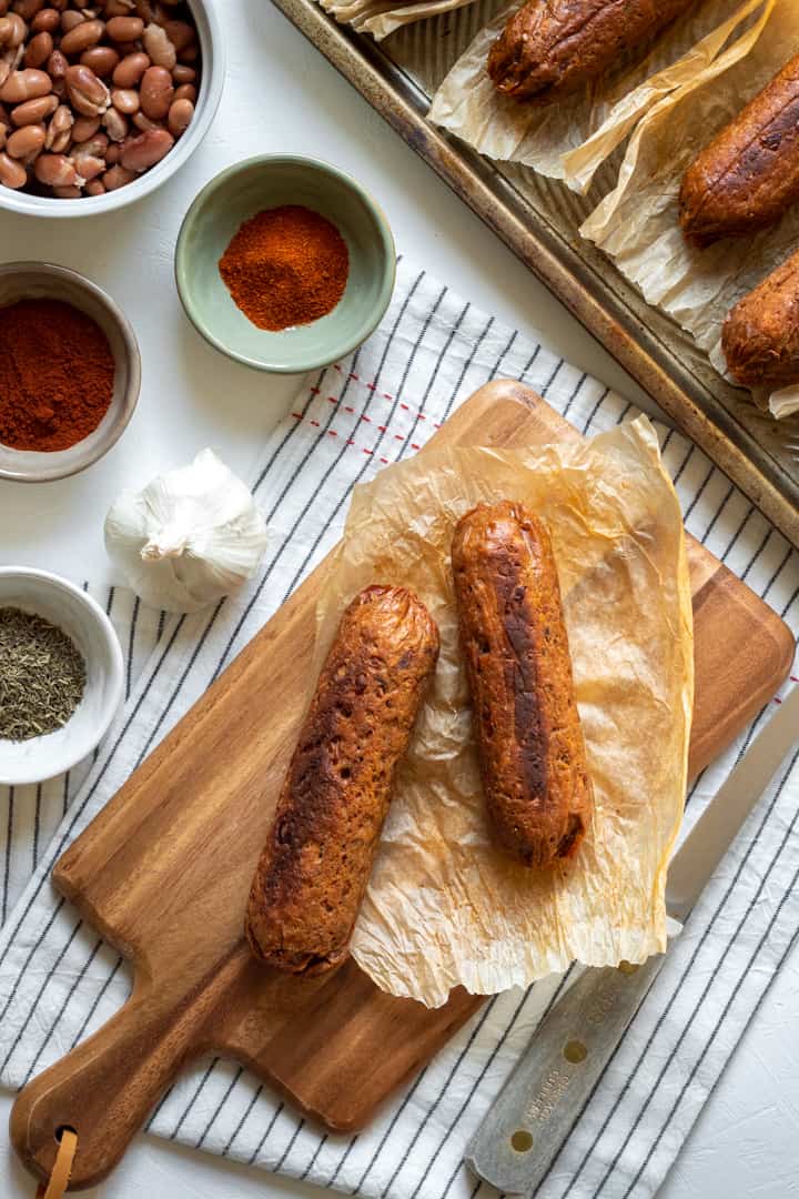 vegan sausages on a cutting board surrounded by spices.