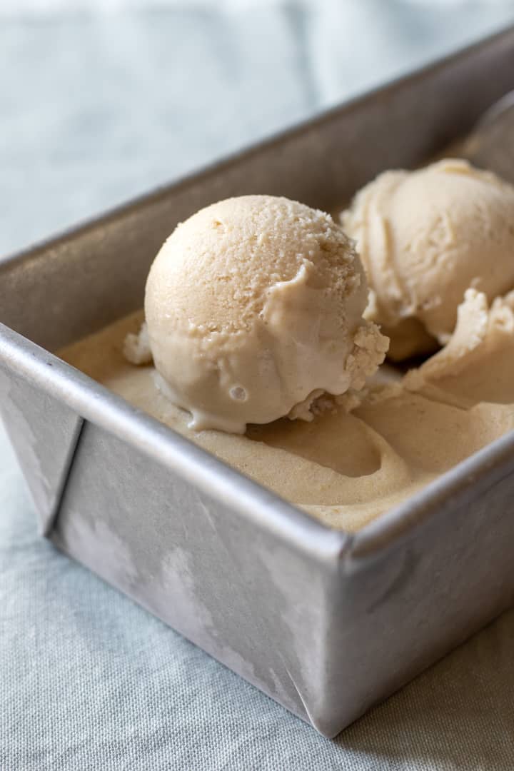 scoops of vegan vanilla ice cream resting in a frozen metal loaf pan.
