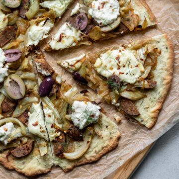 close up of sliced pizza topped with vegan ricotta, sausage, fennel and onion.