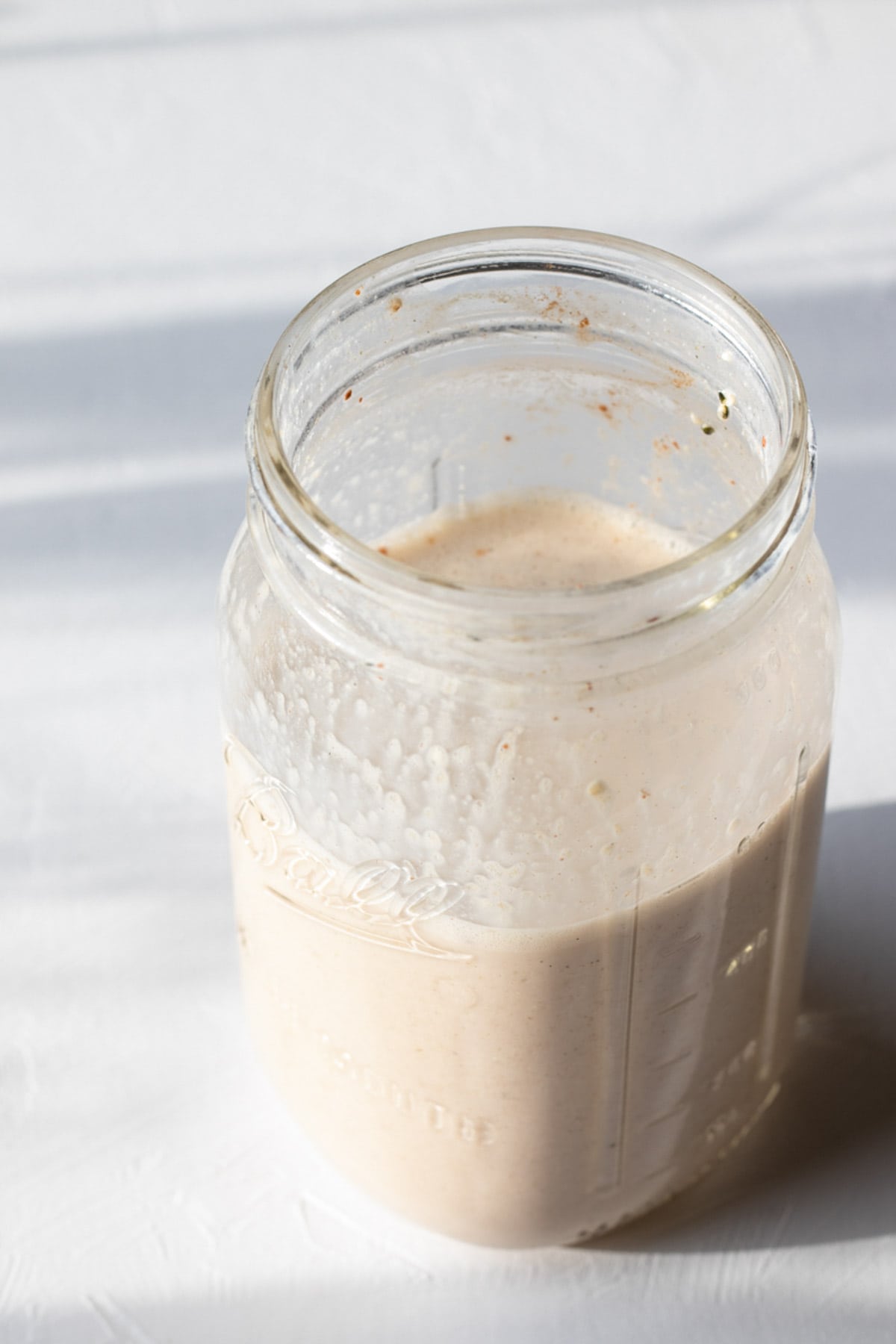 a half empty Ball jar of creamy oat drink.