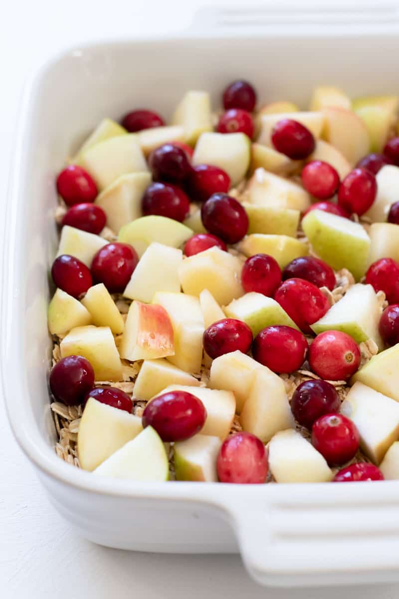 layers of oats, apple, and cranberries in a baking dish.