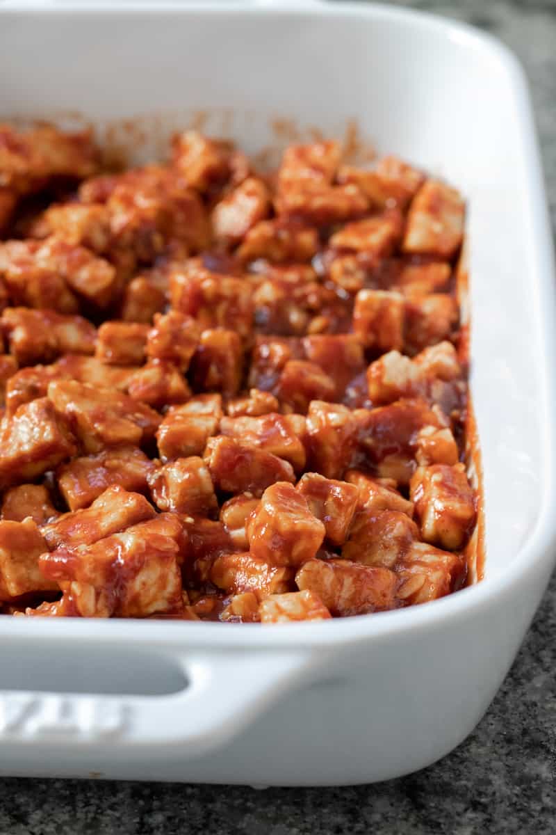 cubed tempeh coated in BBQ sauce ready to be baked.