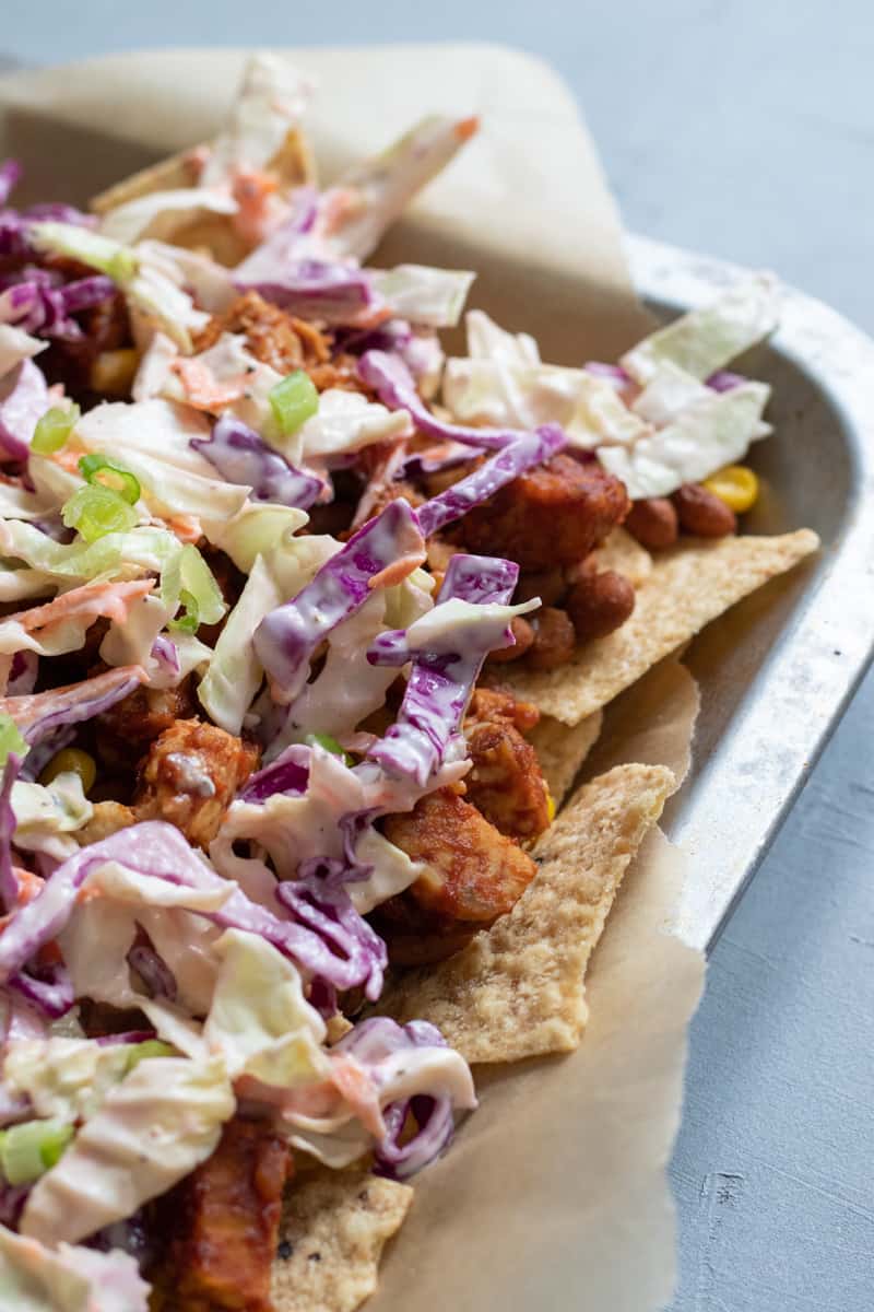 start by layering tortilla chips, then beans, tempeh, and slaw; repeat.