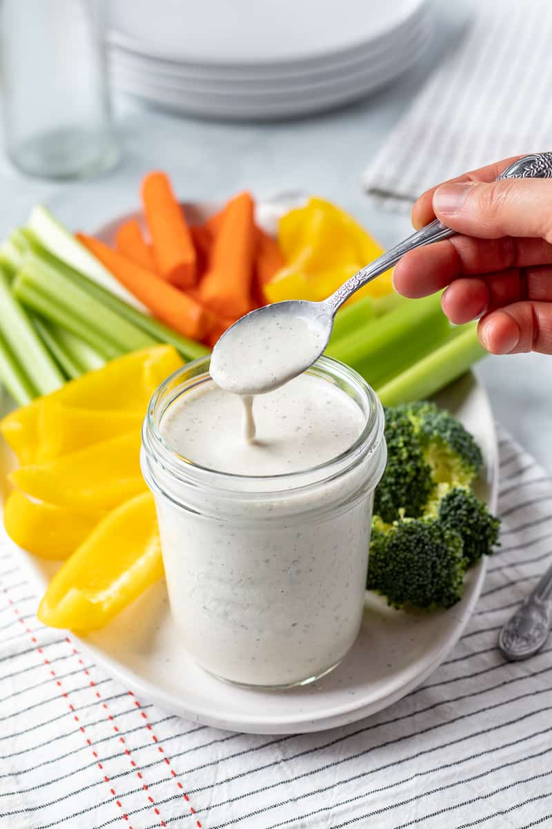 drizzling creamy vegan ranch from a spoon.