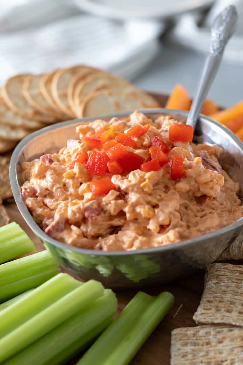 pimento cheese on a platter surrounded by celery and crackers.