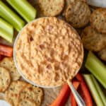 A small bowl filled with creamy dairy free pimento cheese with veggies and crackers on the side.