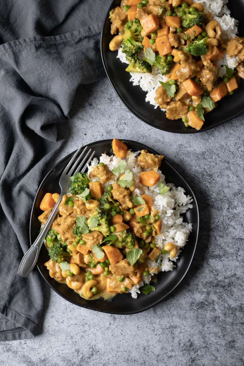 vegan Massaman Curried Seitan with peas, sweet potato and broccoli on a plate.