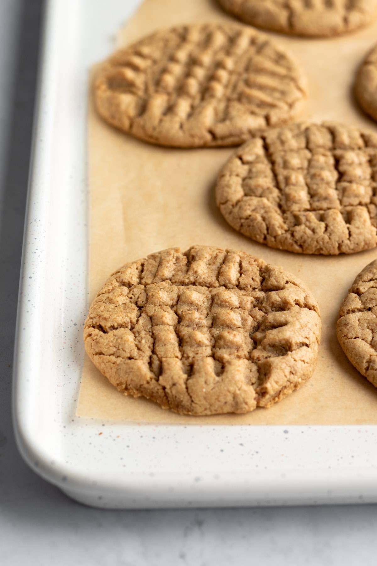 Freshly baked peanut butter cookies on a parchment lined baking sheet.
