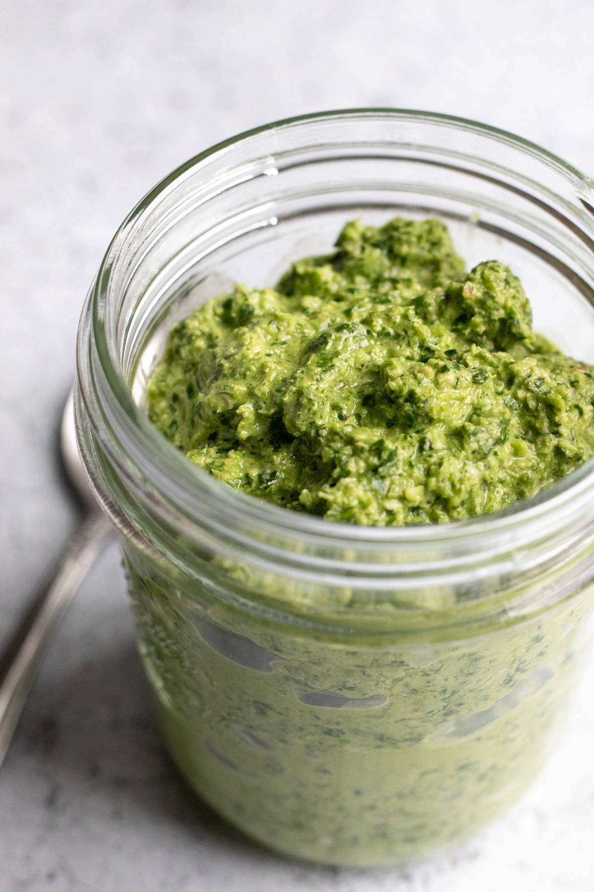 colorful and thick green pesto in a glass jar.