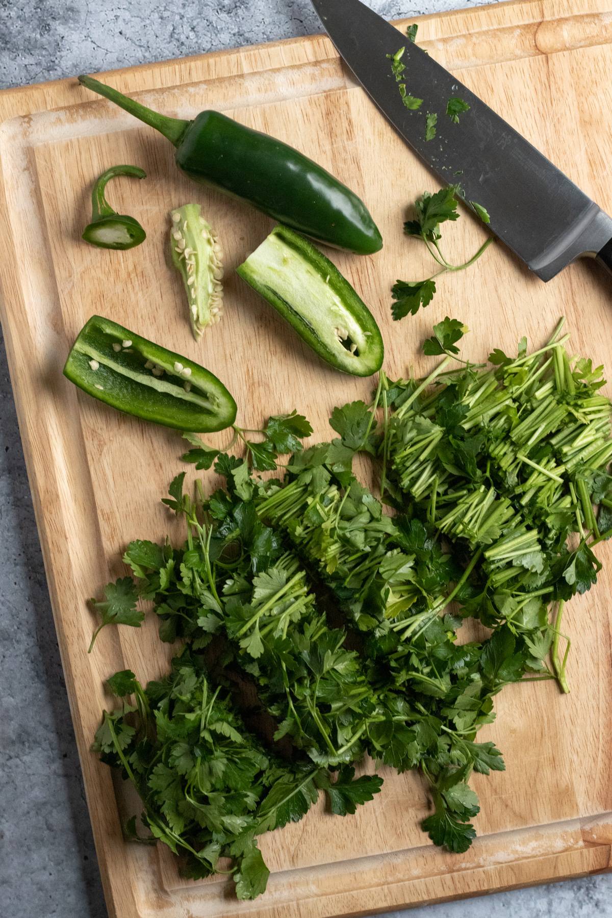 roughly chopped parsley and jalapeños on a cutting board.