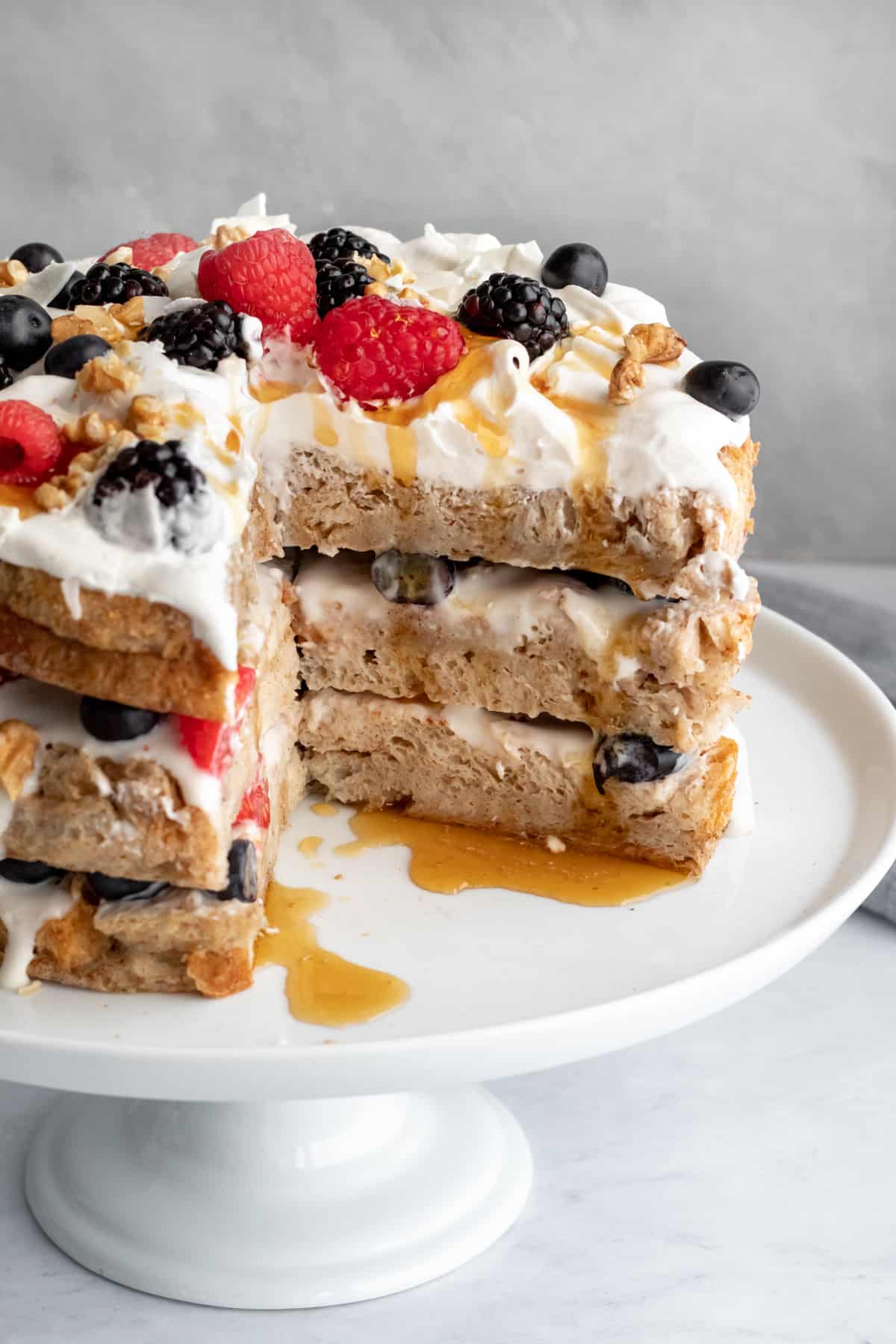 vegan french toast cake layered with yogurt and berries and drizzled with maple syrup