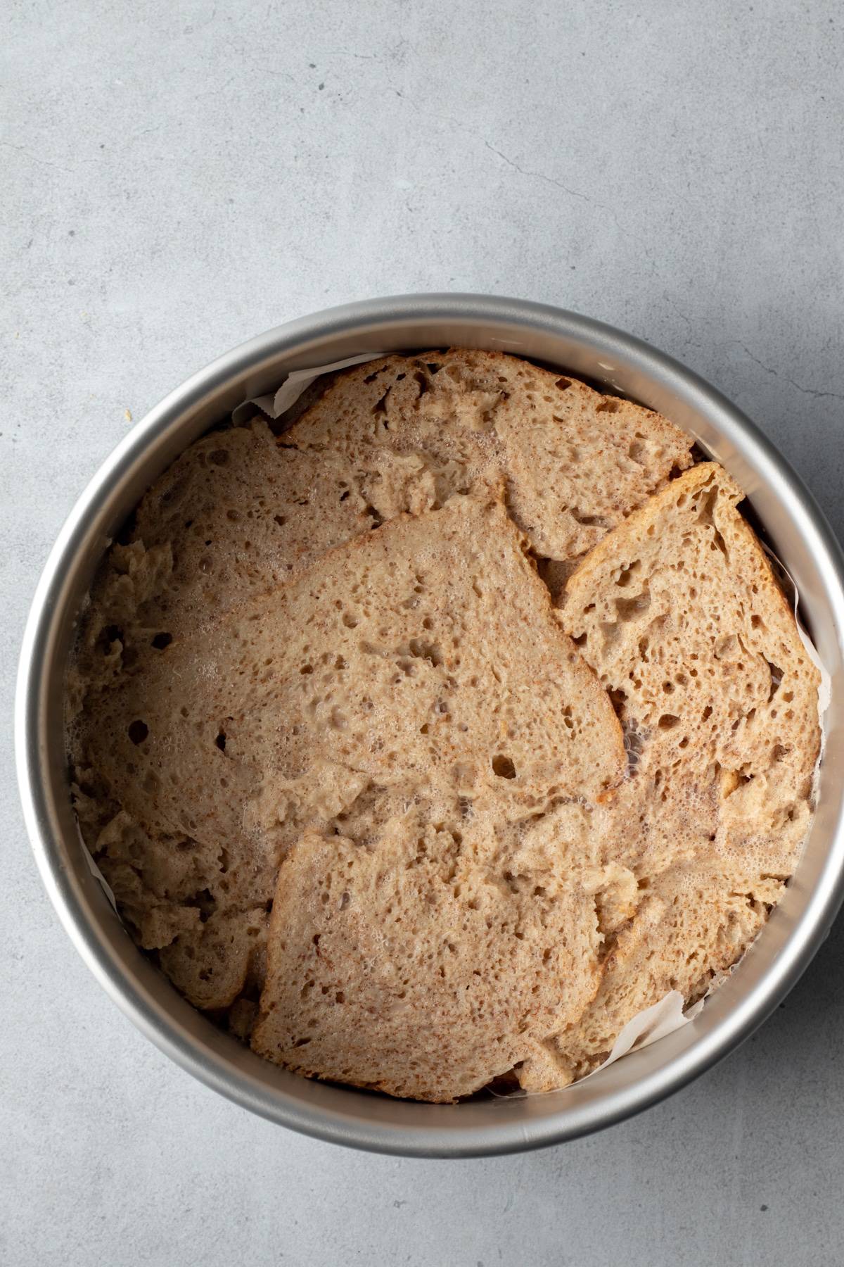 soaked pieces of bread torn to fit inside a round cake pan.