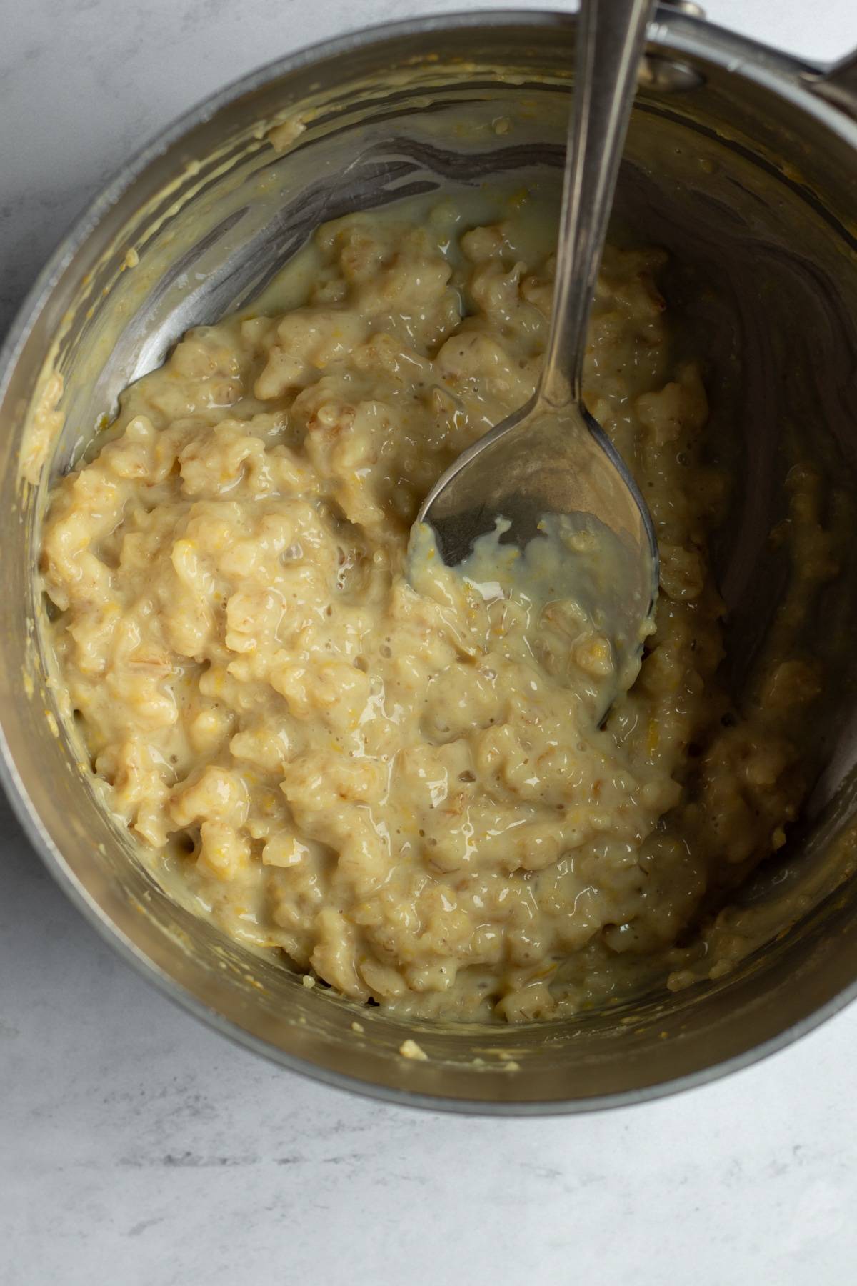 cooked oatmeal with lemon zest in a small pot.