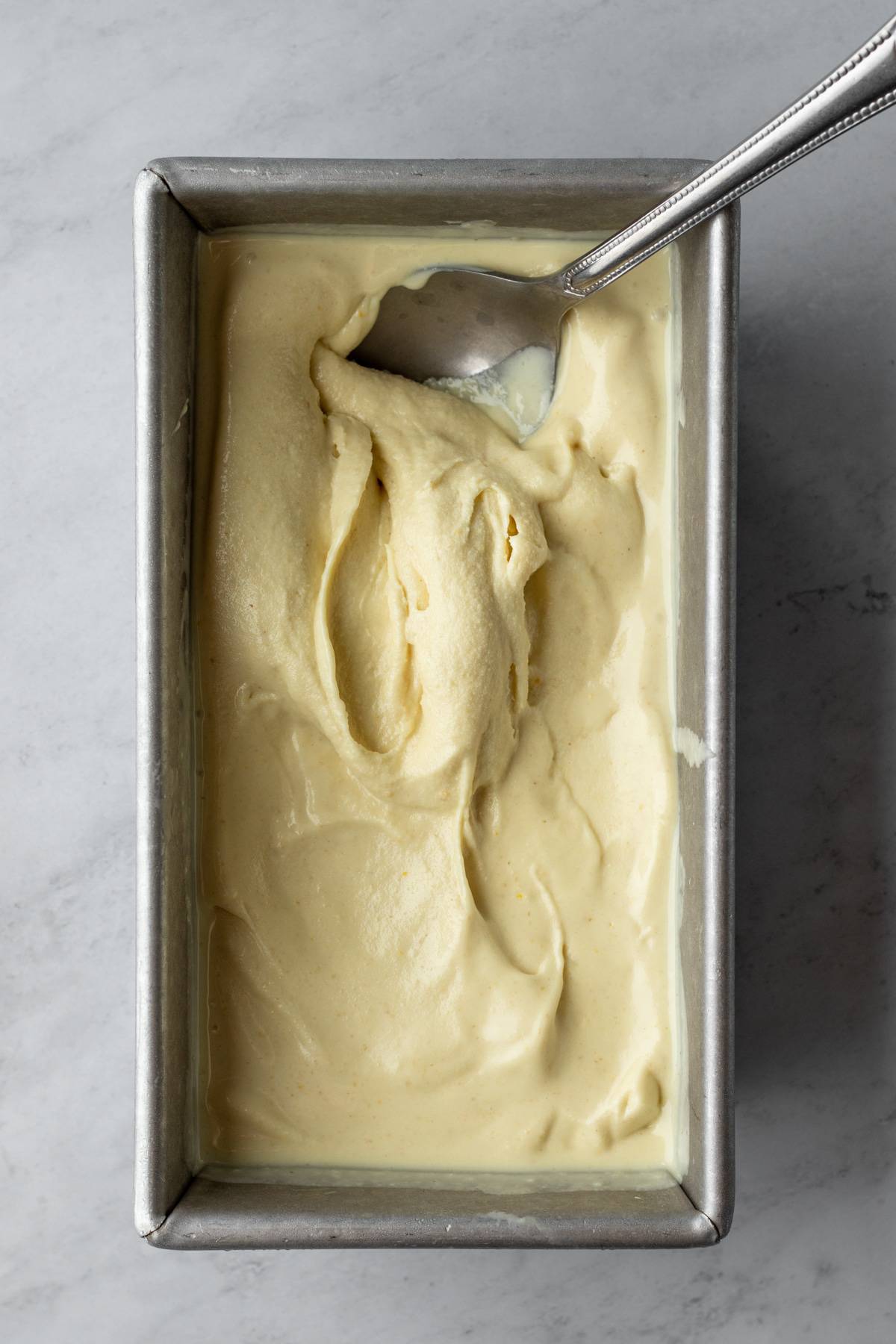Just-churned vegan ice cream with a soft-serve consistency spread in a loaf pan.