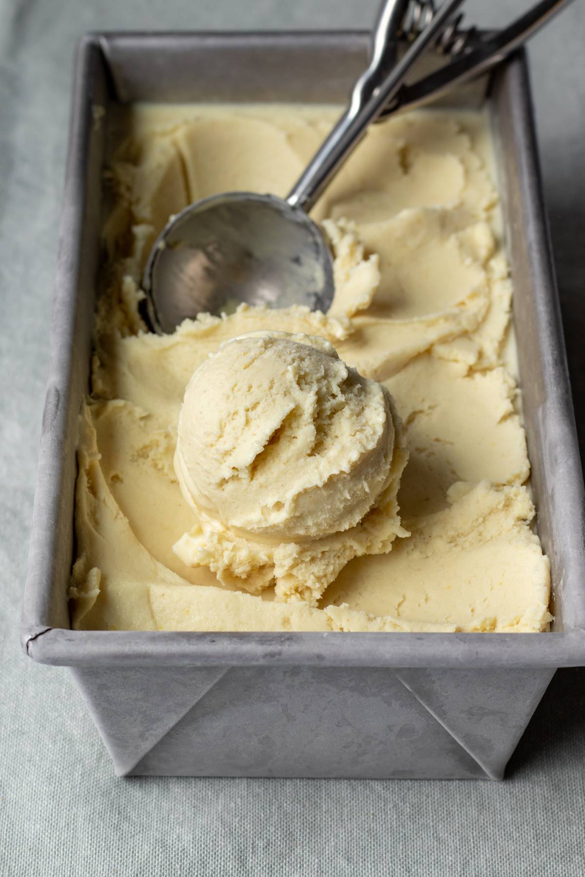 scooping up frozen ice cream from a metal loaf pan.