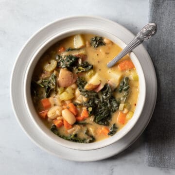 close up overhead view of veggie-filled Tuscan soup in a white bowl.