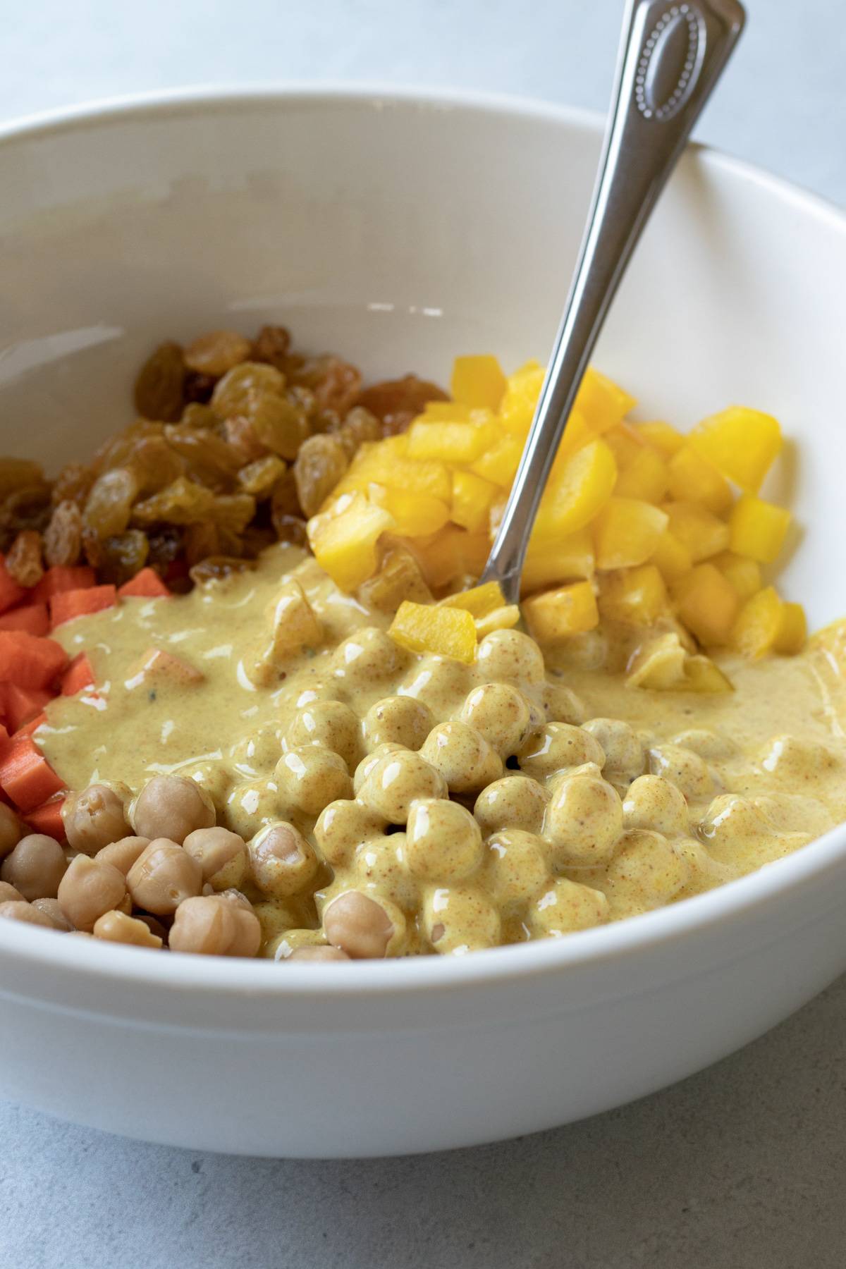 stirring chickpeas, veggies, and curry mayo together in a large bowl.