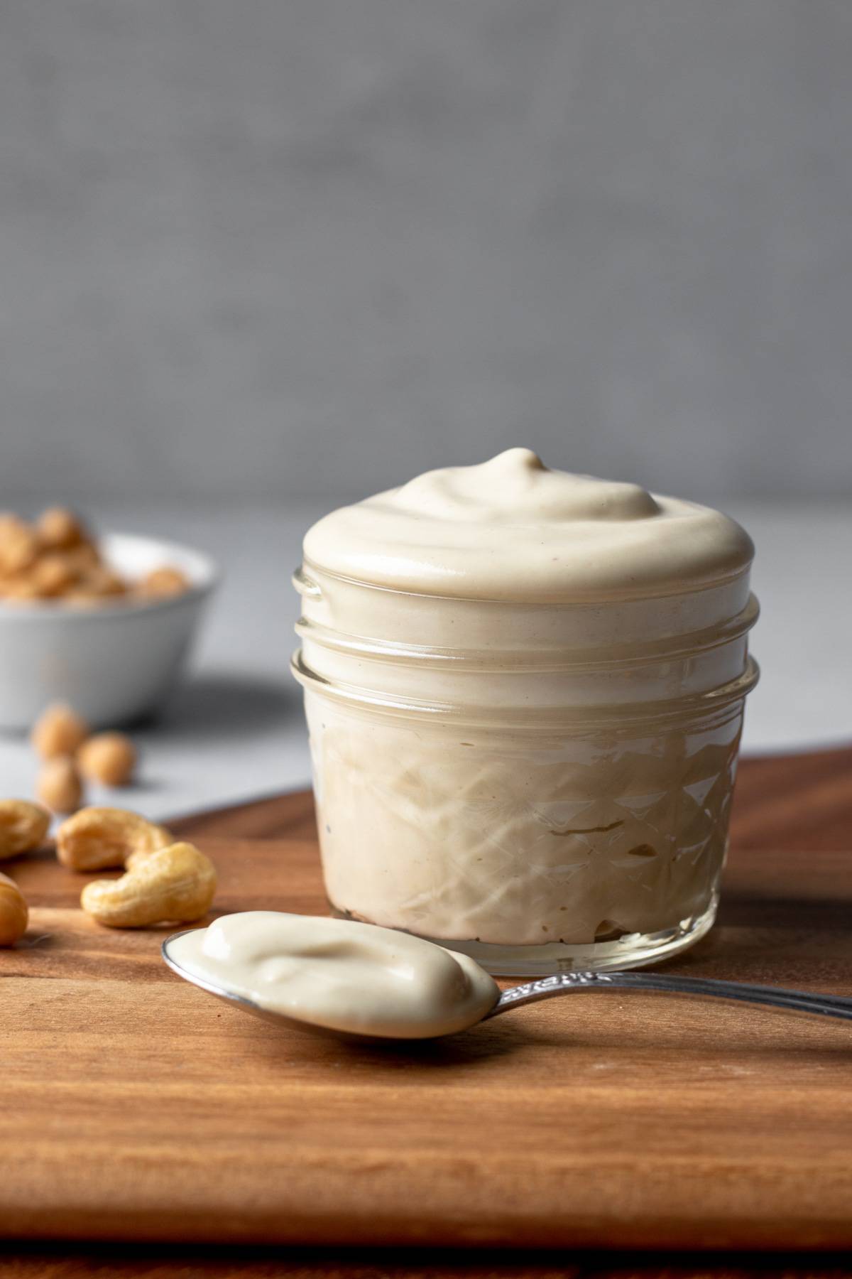 homemade oil-free vegan mayo in a small jar with a spoonful of mayo resting beside it.