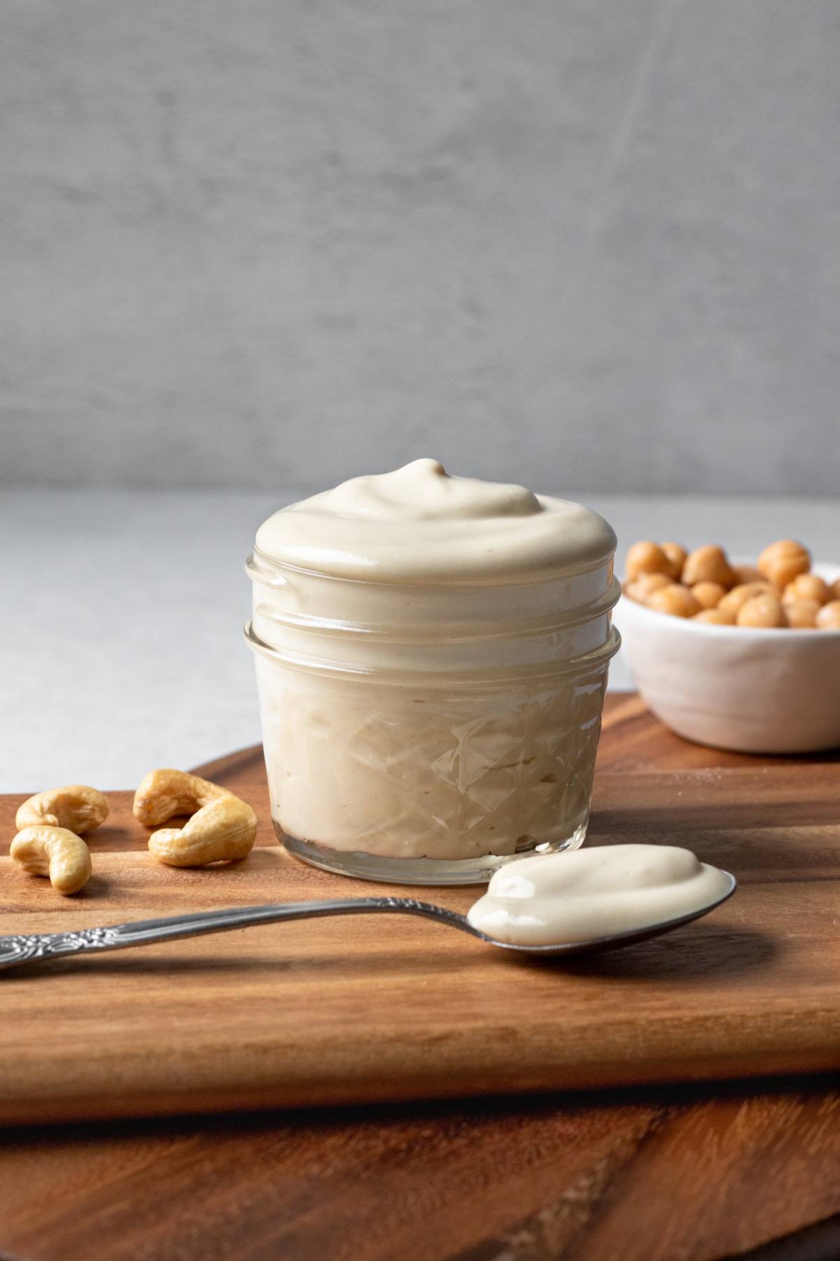 aquafaba mayo in a small jar on a wooden board.