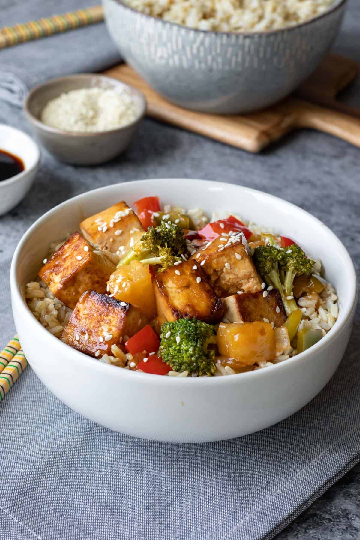 sweet and sour tofu with broccoli, pineapple,and rice in a white bowl.