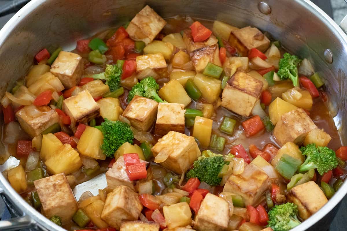 sautéed vegetables, seared tofu, and sweet and sour sauce in pan.