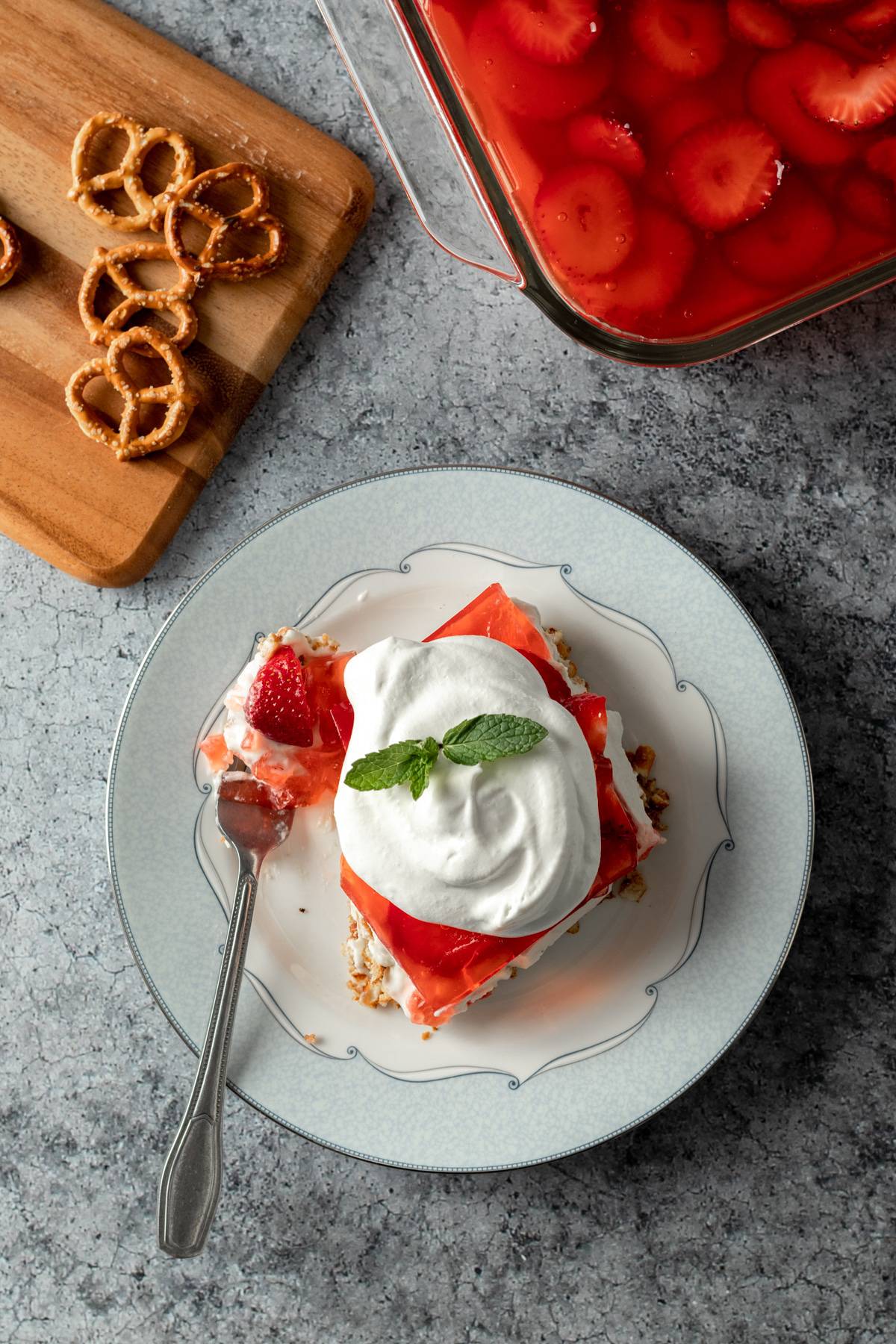 vegan pretzel salad on a plate topped with coconut whip and mint.