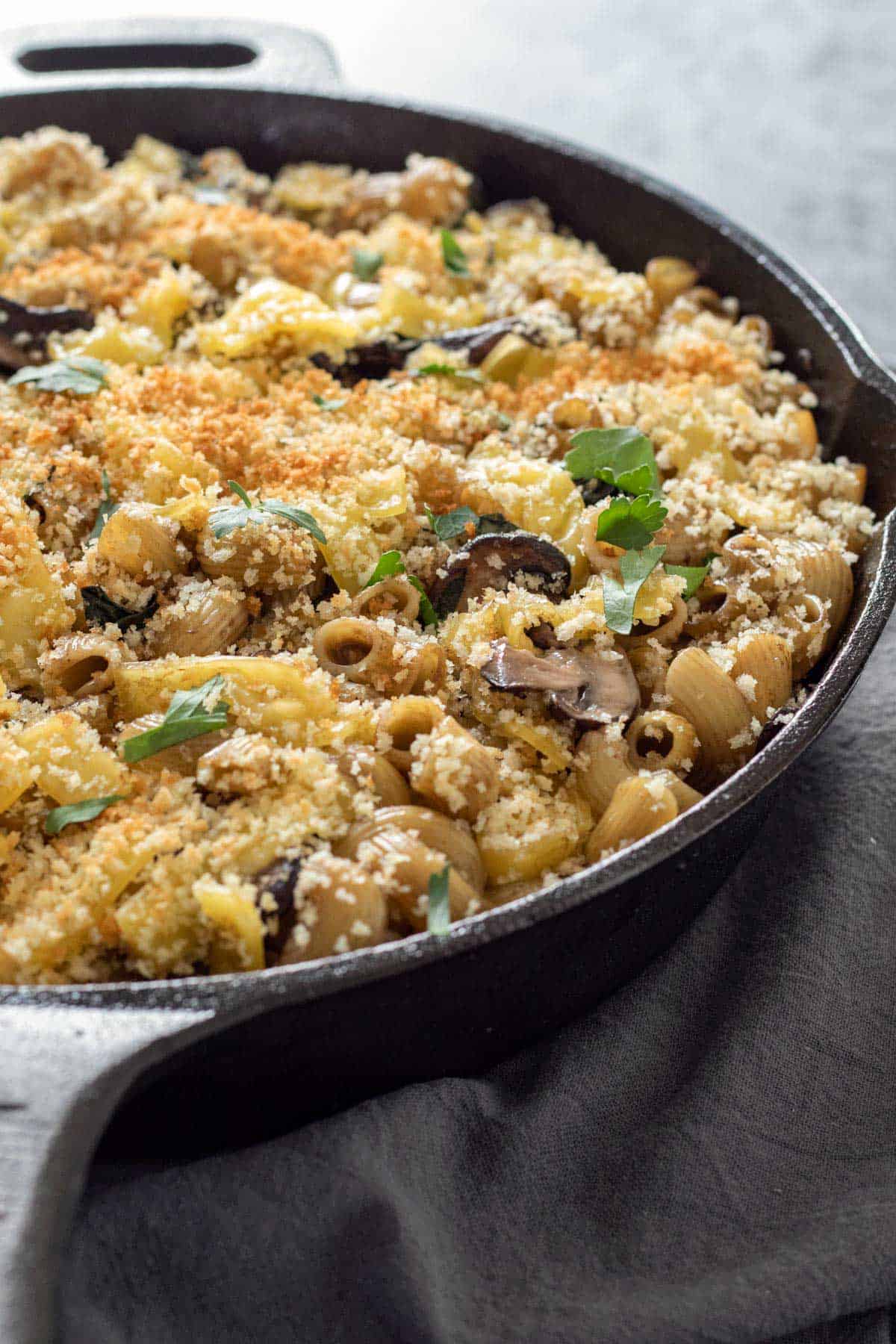 baked vegan mushroom pasta topped with breadcrumbs in a cast iron skillet.