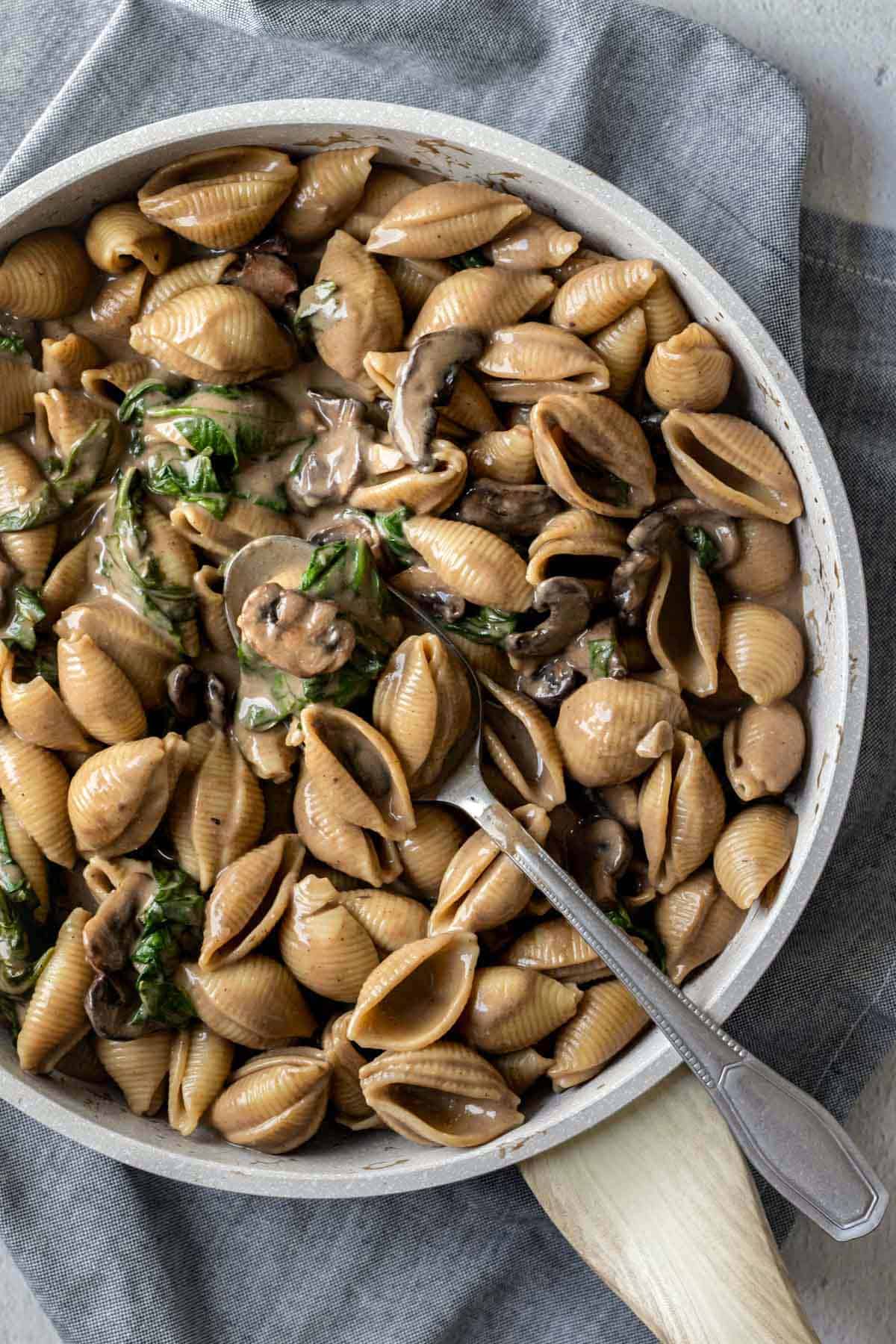 pasta shells and spinach coated in a vegan mushroom sauce.