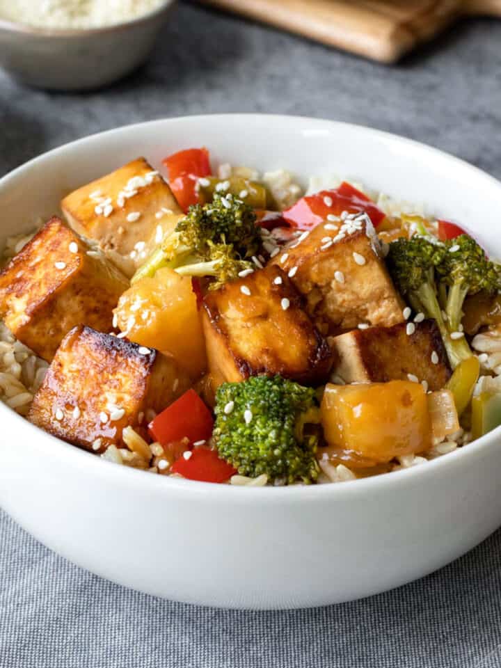 A serving of rice and sweet and sour tofu in a bowl.