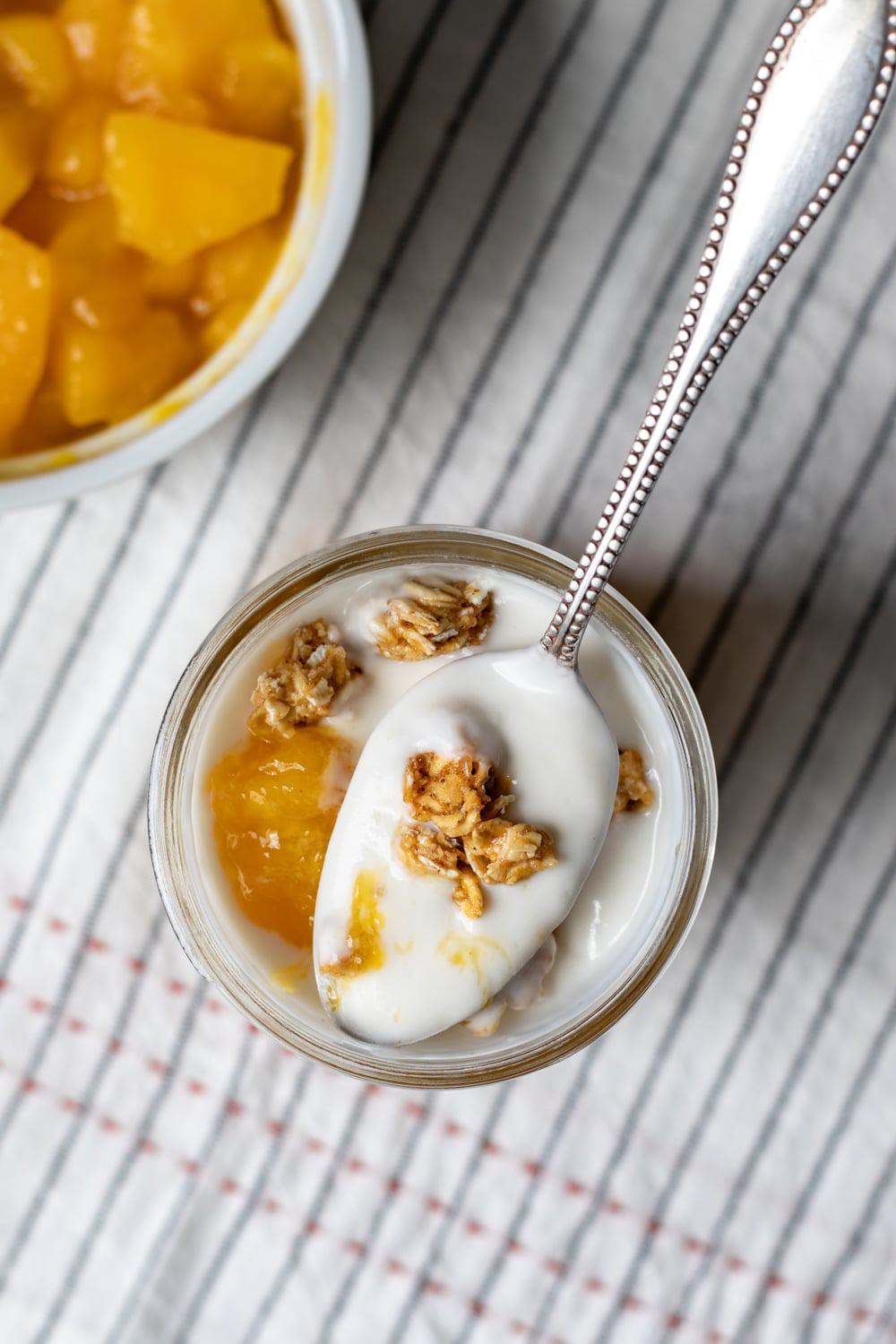 overhead shot of a spoonful of creamy yogurt with granola and mango