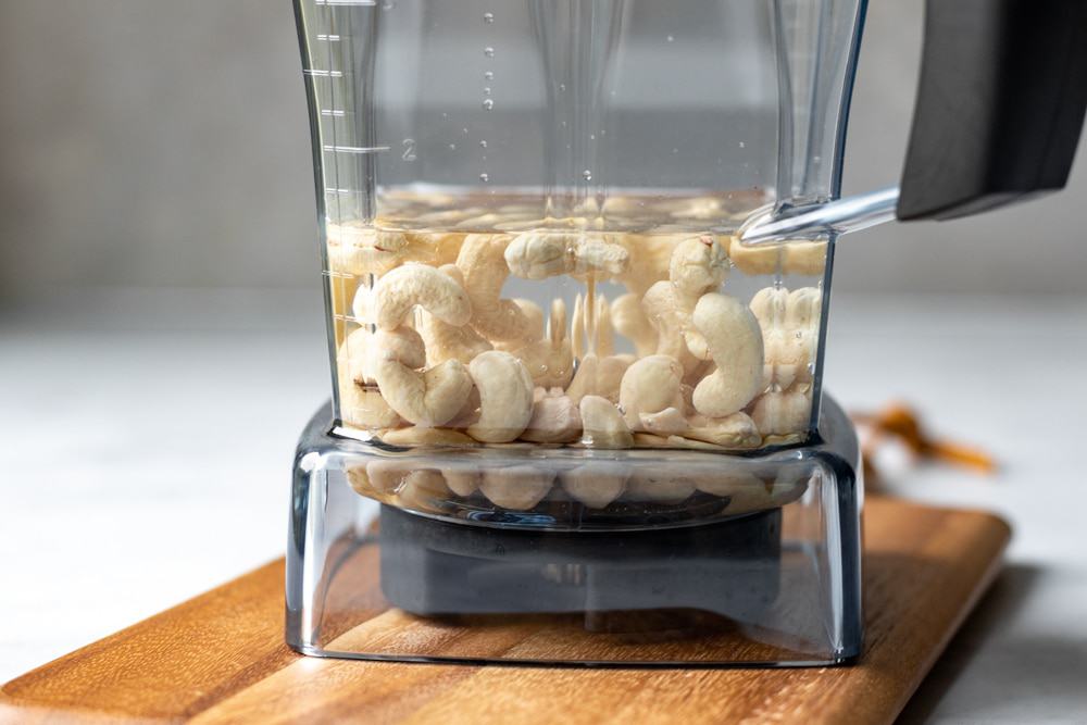 cashews floating in water in a blender jug