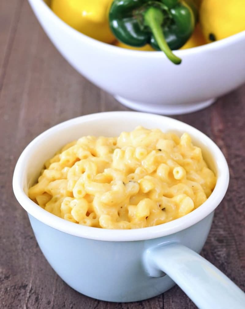 lemony mac in a white dish with lemons and a pepper in background.