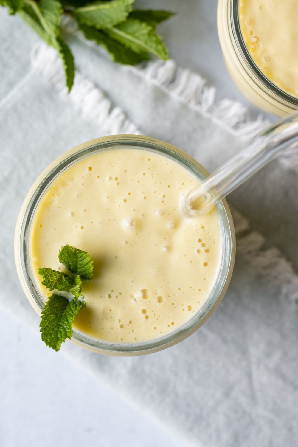 overhead close up of smoothie in a jar with mint and a glass straw.