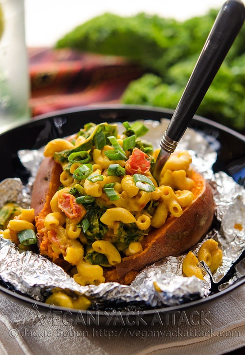 baked sweet potato on foil filled with mac and cheese and green onion.