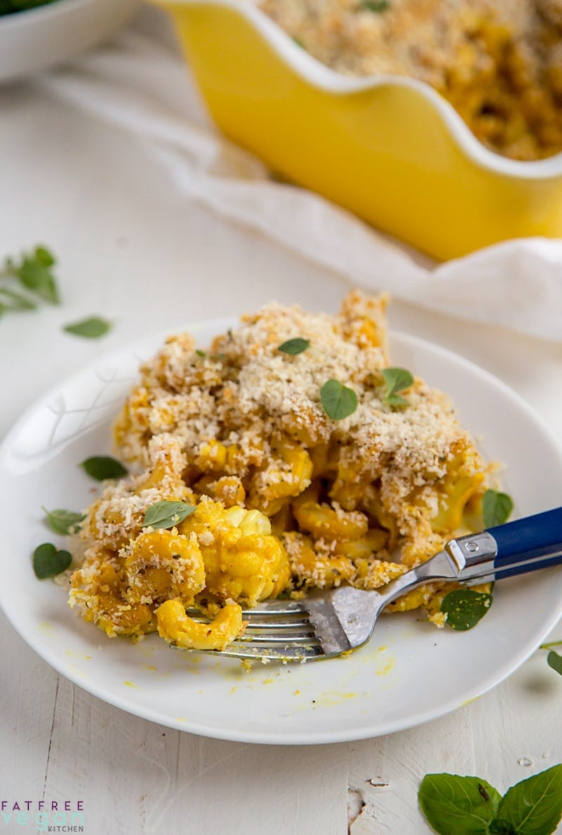 baking dish in background with a serving of baked mac and cheese on a small plate in foreground.