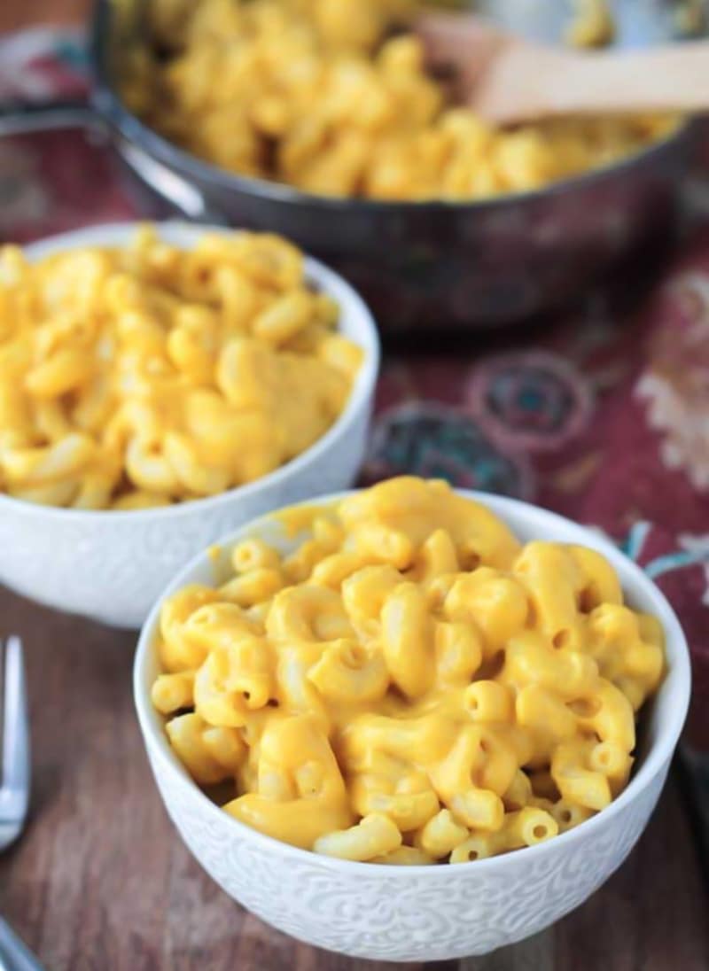 servings of squash mac and cheese in white bowls with a pot in background.