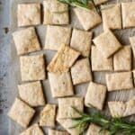 Crackers and sprigs of rosemary on a baking sheet.