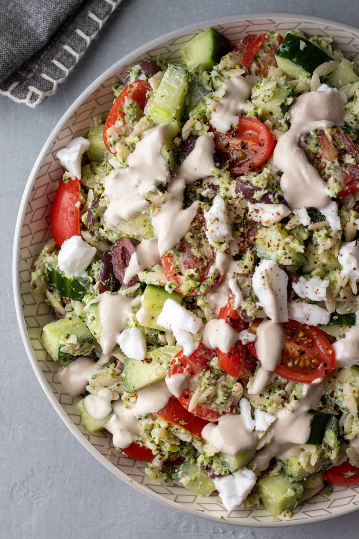 overhead view of creamy orzo salad with olive dressing drizzled on top.