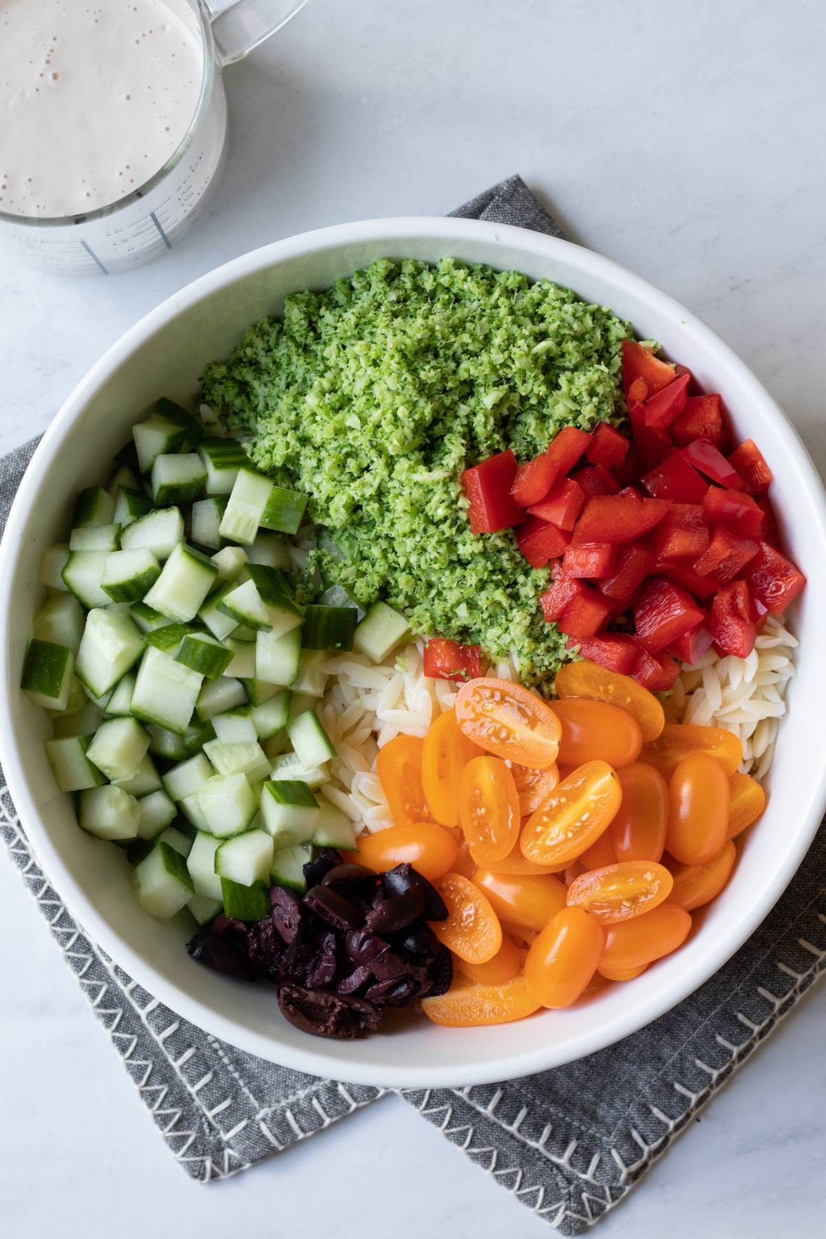 orzo salad ingredients in a large bowl before mixing together.