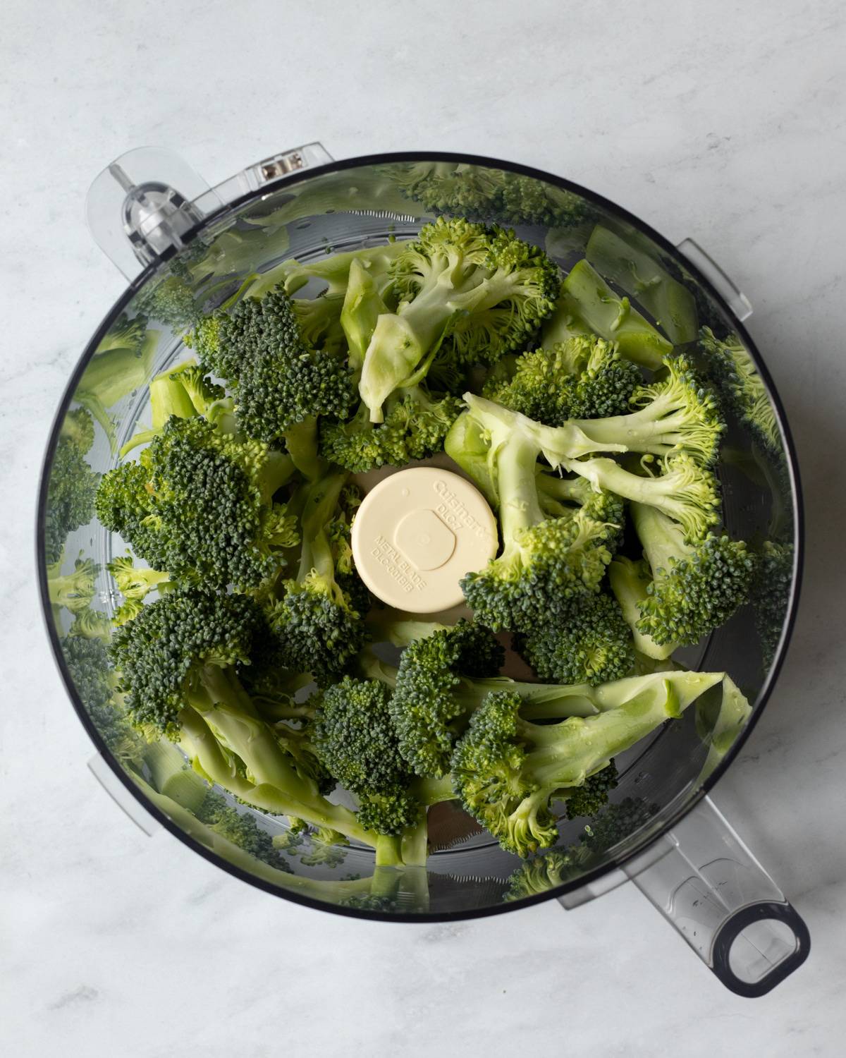 food processor bowl filled with broccoli florets.