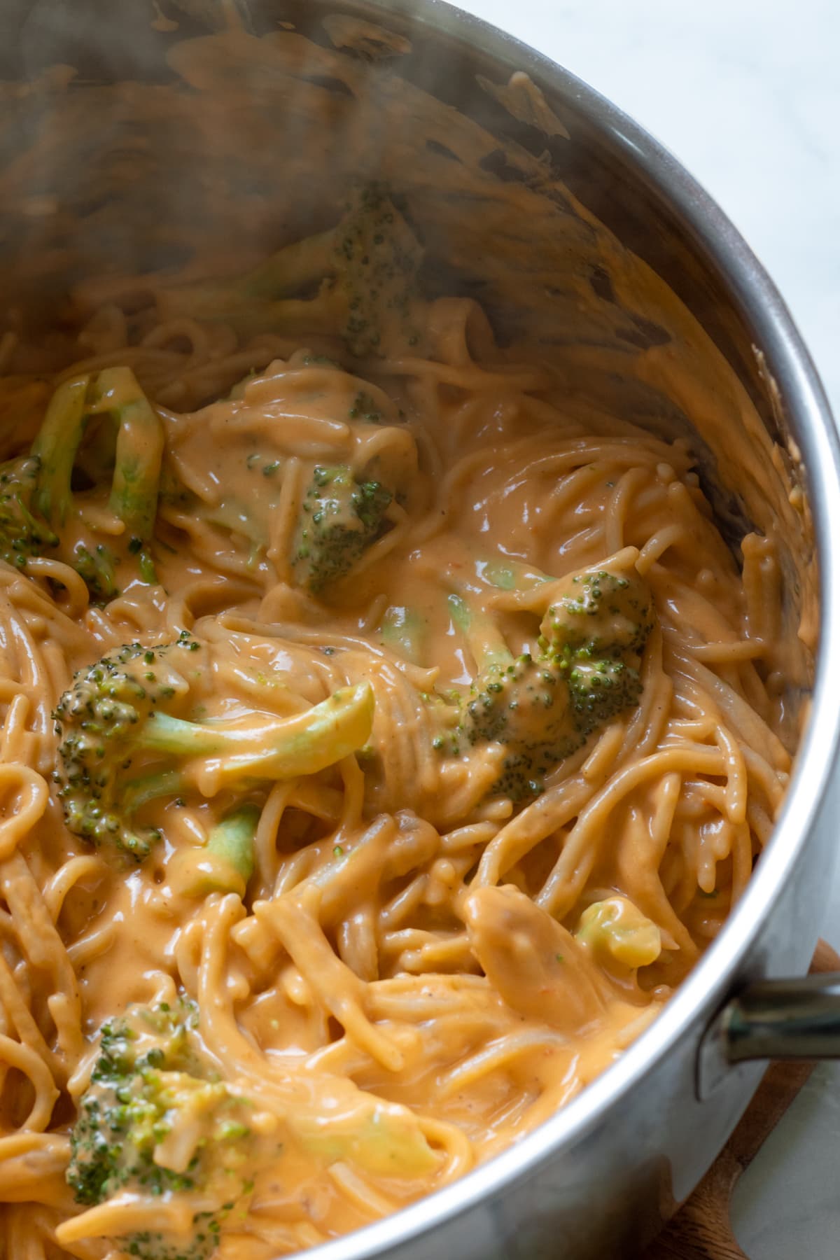 spaghetti and broccoli in a pot coated with vegan cheese sauce.